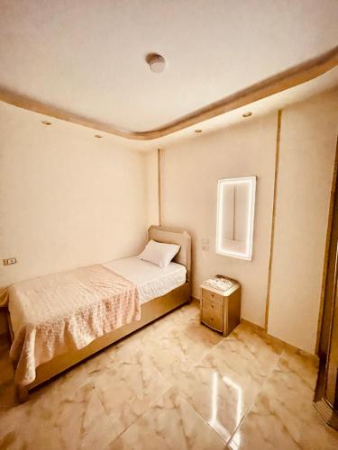 a small bedroom with a bed and a night stand at El mansour hotel apartmen 84 in Mansoura