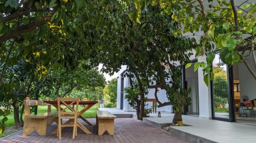 een patio met een tafel en banken onder een boom bij Le Jardin de Temeni in Aigio