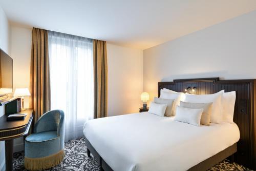 フォンテーヌブローにあるHôtel & SPA Napoléonの大きなベッドと椅子が備わるホテルルームです。