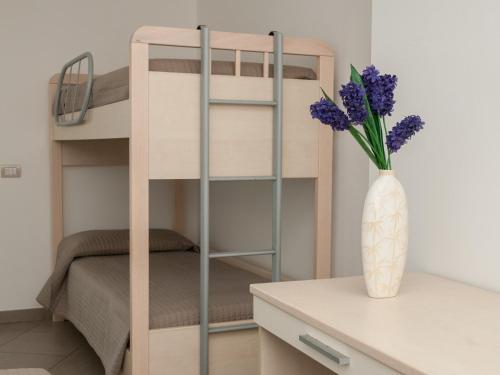 a room with a bunk bed and a vase with purple flowers at Residence Art in Rimini