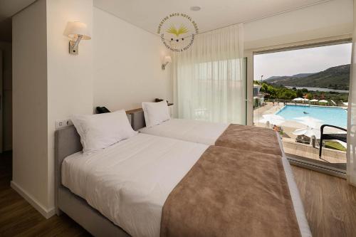 - une chambre avec un lit et une vue sur la piscine dans l'établissement Rupestre Arts Hotel Ródão, à Vila Velha de Ródão