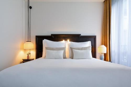 a large white bed with two pillows and two lamps at Hôtel & SPA Napoléon in Fontainebleau