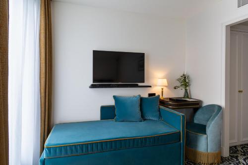 a room with a blue couch and a flat screen tv at Hôtel & SPA Napoléon in Fontainebleau