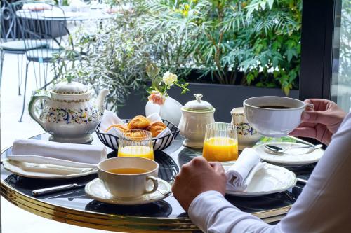 a table with cups and plates of food on it at Hôtel & SPA Napoléon in Fontainebleau