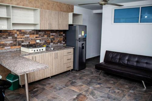 uma cozinha com um frigorífico preto e um sofá em Aw Hotel Palm Bay Bello Horizonte em Santa Marta