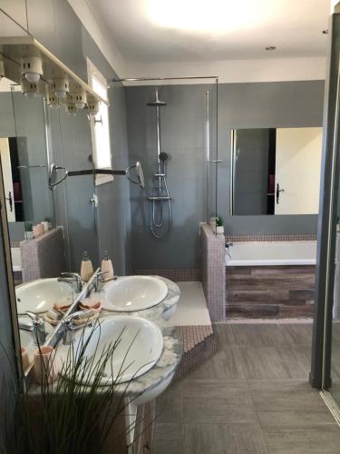 La salle de bains est pourvue de 2 lavabos, d'une douche et d'une baignoire. dans l'établissement Maison 3 chambres au calme avec piscine, à La Fare-les-Oliviers