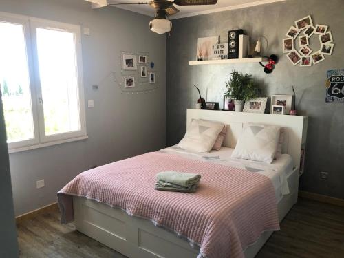 a bedroom with a bed with a pink blanket at Maison 3 chambres au calme avec piscine in La Fare-les-Oliviers