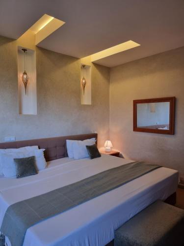 um quarto com uma grande cama branca e uma mesa de cabeceira em Les terrasses du Lac Marrakech em Lalla Takerkoust