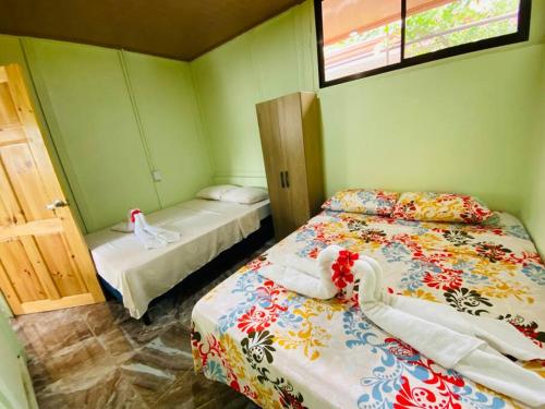 2 Betten in einem Zimmer mit grünen Wänden in der Unterkunft Casita Colorada, Sierpe de Osa in Sierpe