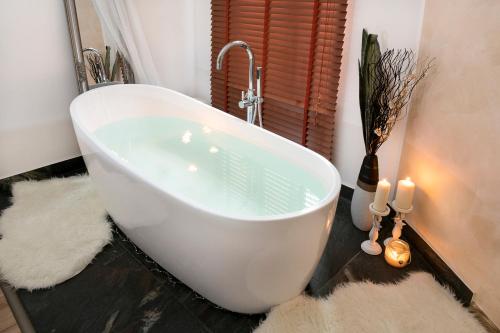 a white bath tub in a bathroom with two candles at STING Boutique Apartments in Ostrava