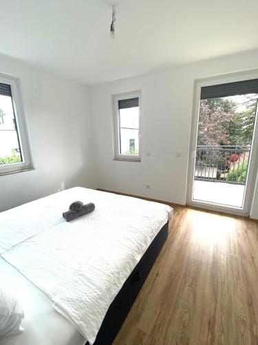 a white bedroom with a large bed and two windows at Neubauwohnung Lura 2b - für 5 Personen in Vienna