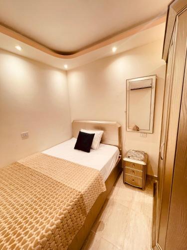 a small bedroom with a bed and a mirror at El mansour hotel apartmen 84 in Mansoura