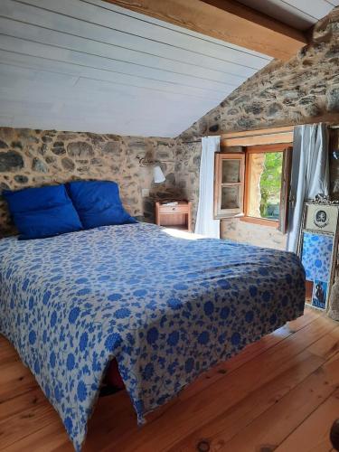 - une chambre avec un lit bleu dans un mur en pierre dans l'établissement Maison traditionnelle catalane avec jardin, à Thuès-entre-Valls