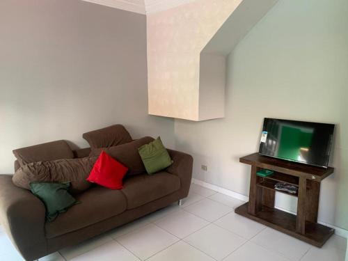 - un salon avec un canapé brun et une télévision dans l'établissement Casa Duplex Maria Farinha, à Paulista