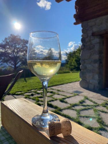a glass of white wine sitting on a wooden table at Baita dei Fovi in Baselga di Pinè