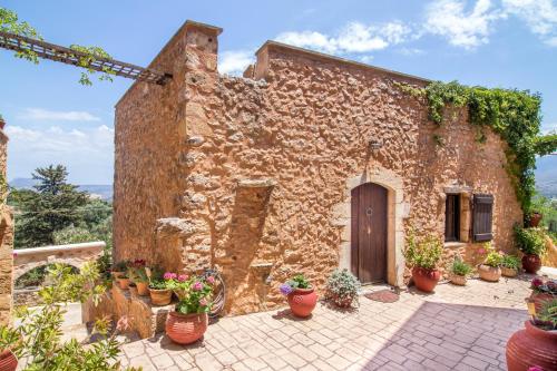 an old stone house with potted plants in front of it at Samonas Traditional Villas in Samonás