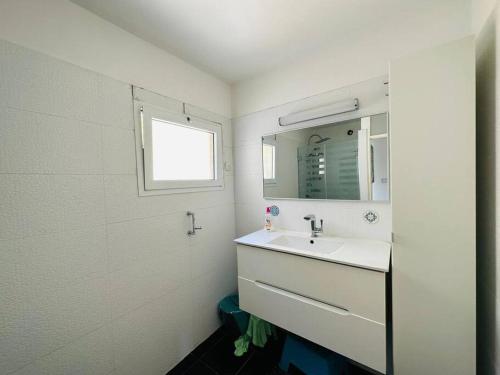 a white bathroom with a sink and a mirror at Great 2 BR apartment view to the garden in Bat Yam