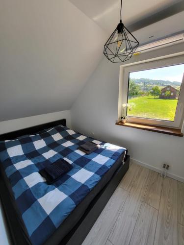 a bedroom with a checkered bed and a window at Domek w Paszynie - Sauna i Gorąca balia in Paszyn