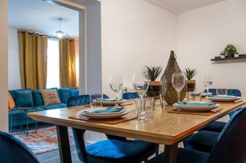 una mesa de madera con copas de vino y sillas azules en Harvest House - TV in every bedroom! en Swansea