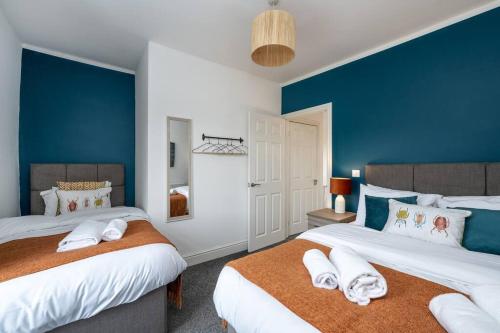 2 camas en un dormitorio con paredes azules en Harvest House - TV in every bedroom! en Swansea