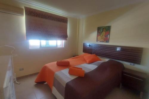 1 dormitorio con cama con sábanas de color naranja y ventana en Apartment with view, wifi and pool in Arguineguin, en Arguineguín