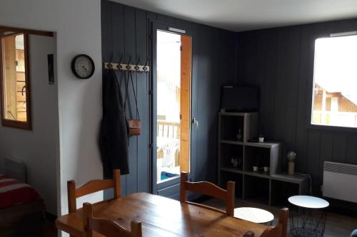 a dining room with a table and a clock on the wall at APPARTEMENT PIEDS DE PISTE - 4-6 PERSONNES in La Chal