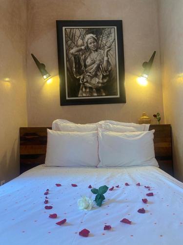 a bed with flowers on it with a picture on the wall at Riad des Fragrances dar el Bacha in Marrakech