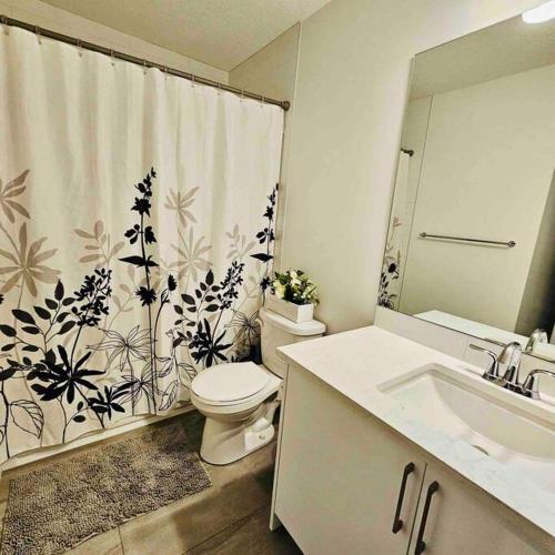 a bathroom with a toilet and a sink and a shower curtain at Cozy 1 Bedroom Basement Apt in SE Calgary in Calgary