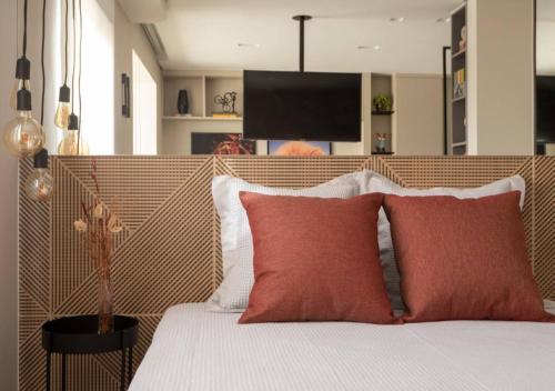 a bedroom with a bed with two red pillows at Charming Studio - Guarulhos, near the GRU Airport in Guarulhos