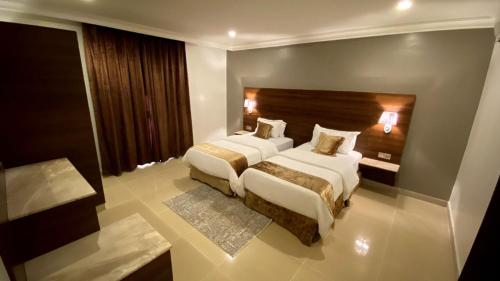 een hotelkamer met 2 bedden en een hoofdeinde bij البستان للأجنحة الفندقية in Al Hofuf
