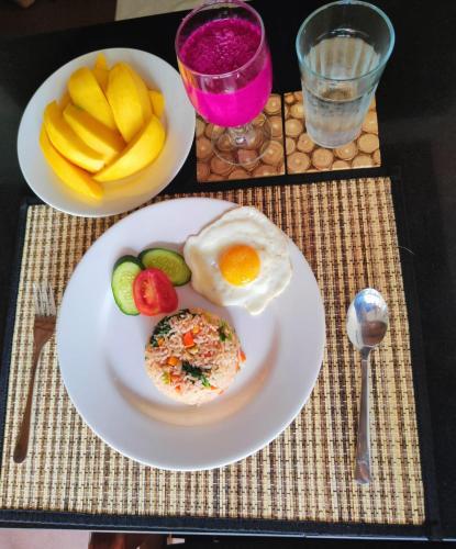 a plate of food with an egg and fruit on a table at Villa BlueLove Seririt in Banjar