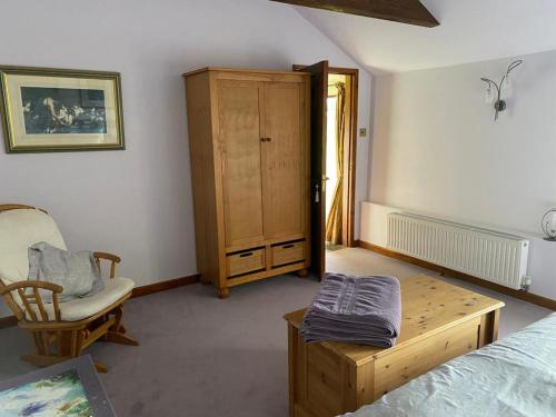 a bedroom with a bed and a chair and a cabinet at The Tool Shed in Wimborne Minster