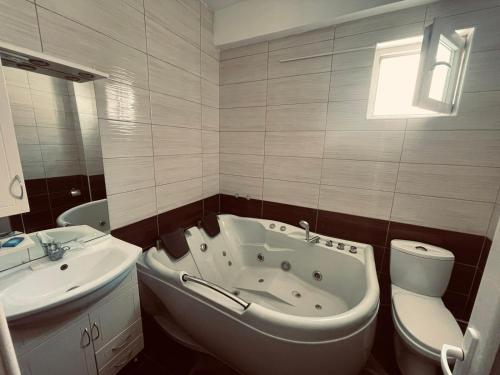 y baño con bañera, aseo y lavamanos. en Hotel Konstantin, en Pristina