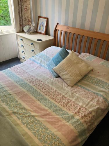 a bed with a quilt and pillows on it at Westbrook-Homestay in Swansea