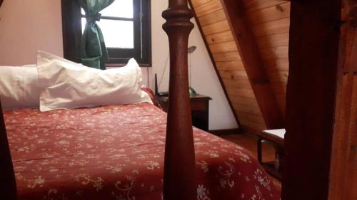 a bedroom with a bed with a red comforter and a window at Ala de Colibri in Ramallo