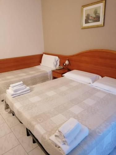 two beds in a hotel room with towels on them at Il Leone D'Oro in Telgate