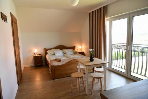 a bedroom with a bed and a table and a balcony at Dobranocka Noclegi - blisko Energylandia in Spytkowice