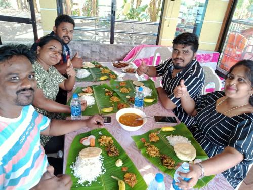 a group of people sitting at a table eating food at Beach Paradise Day Cruise Houseboat in Alleppey