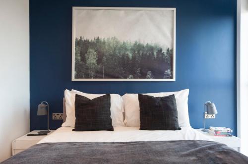 een slaapkamer met blauwe muren en een bed met witte kussens bij Top Floor Apt - 2 Bed/2 Bath + Private Balcony in Londen