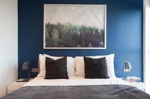 a bedroom with blue walls and a bed with white pillows at Modern 12th Floor | Balcony Striking London View in London