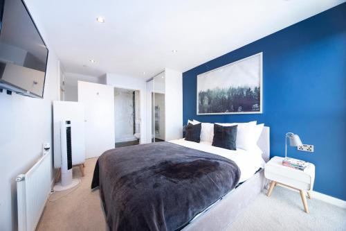 a bedroom with a large bed with a blue wall at Modern 12th Floor | Balcony Striking London View in London