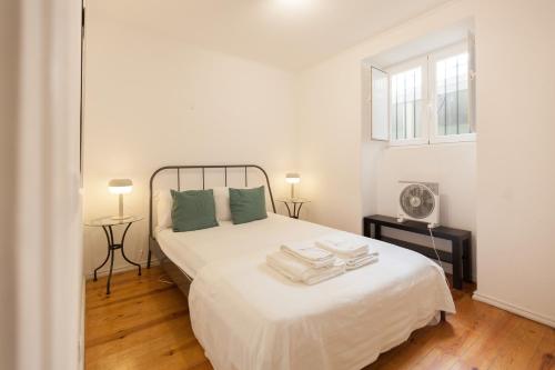 a white bedroom with a large white bed with green pillows at FLH - Central Flat in Bairro Alto in Lisbon