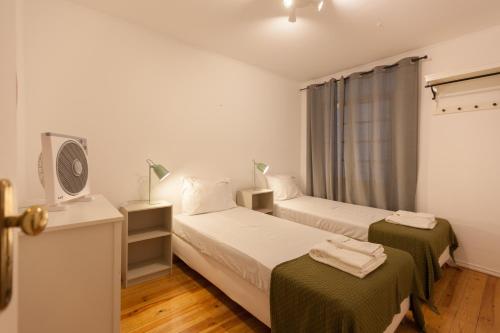 a bedroom with two beds and a tv and a window at FLH - Central Flat in Bairro Alto in Lisbon