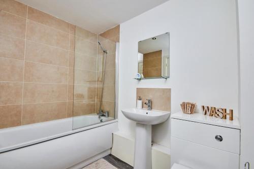 a bathroom with a sink and a bath tub and a sink at Stylish 2 Bed Apartment with Free parking, close to City Centre by Hass Haus in Manchester