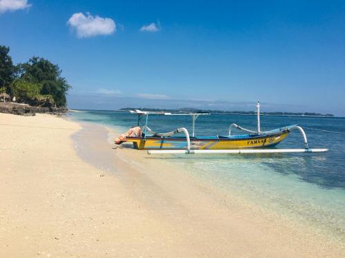 a boat sitting on the shore of a beach at Puring Bungalows in Gili Air
