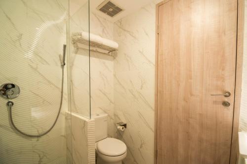 a bathroom with a toilet and a glass shower at Yulia Hotel Managed by HIG in Gorontalo