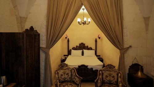 a bedroom with a bed with two chairs and a chandelier at zerzevan hotel in Mardin