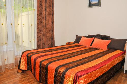1 dormitorio con 1 cama con manta naranja y naranja en Kristinos Apartamentai - Vytauto, en Palanga