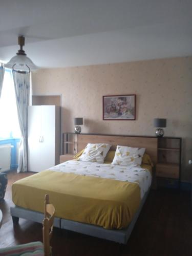 a bedroom with a large bed with a yellow blanket at Chambres d'hôtes les Clématites en Cotentin in Saint-Floxel