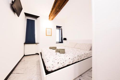 Appartamento La Città Vecchia في جينوا: غرفة نوم بيضاء بها سرير ونافذة